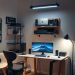 A modern home office setup featuring a desk, computer monitor, speakers, and stylish lighting.