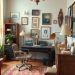 A stylish home office featuring vintage furniture, framed pictures on the walls, a cozy chair, and a patterned rug.