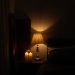 A moody bedroom with a lamp and candles providing soft lighting.