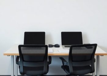 A double desk setup with two black office chairs, designed for collaboration.