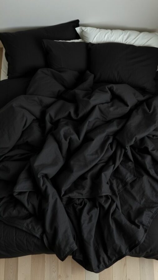 30 Stylish Black Bedroom Ideas 15 A bed with a layered arrangement of crumpled black textiles and pillows