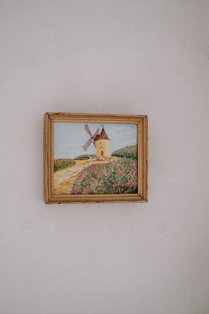 a painting of a windmill hangs on a wall