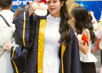 a woman in a graduation gown holding a stuffed animal