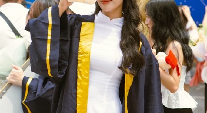 a woman in a graduation gown holding a stuffed animal