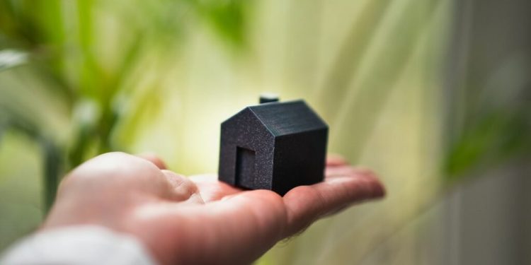 A person holding a small house in their hand