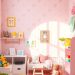A bright and playful children's room with pastel pink wallpaper, colorful toys, and cozy seating.