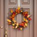 A DIY wreath made of colorful fall leaves hanging on a door.