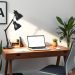 A modern home office desk setup with a laptop, lamp, and plants.