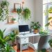 A cozy home office with various green plants, a desk, and a computer.