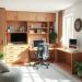 A cozy home office with wooden furniture, a comfortable chair, and plants, featuring a well-organized desk area.