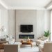 A neutral living room with a patterned accent wall, light furniture, and wooden flooring.