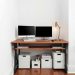 A small home office with a wooden desk, two monitors, and organized under-desk storage boxes.
