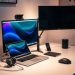 A modern home office setup with a laptop, external monitor, headphones, and a wireless mouse on a clean desk.