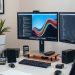 A modern home office setup featuring dual monitors, a laptop, smartphone, and a plant.
