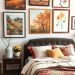 A cozy bedroom with nature-inspired artworks featuring autumn scenes on the wall.