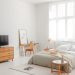 A minimalist bedroom featuring neutral tones, wooden furniture, and natural light.