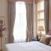Stylish window treatments in a guest bedroom with beige curtains and a valance.