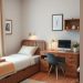 A cozy small bedroom featuring a bed with storage drawers, a compact desk, and warm wooden tones.