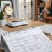 A home office desk with a planner open, a clock, and a laptop, showcasing an organized workspace.