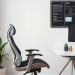 A modern ergonomic office chair beside a sleek desk in a home office setting.