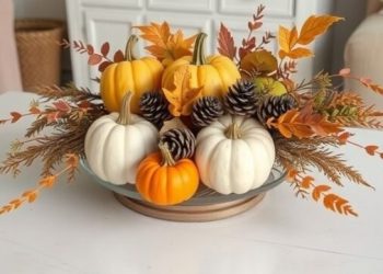 A cozy fall centerpiece featuring pumpkins, pinecones, and autumn leaves.