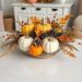 A cozy fall centerpiece featuring pumpkins, pinecones, and autumn leaves.
