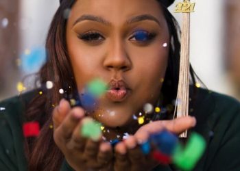 a woman in a graduation cap blowing bubbles