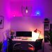 A modern home office with colorful lighting fixtures, including a unique pendant light and a red desk lamp.