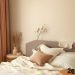A cozy bedroom with neutral colors, featuring beige walls, soft bedding, and natural decor.