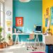 A bright home office with teal and yellow walls, a white desk, and a pink rug.
