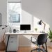 A minimalist home office with a desk, computer, lamp, and plants, featuring natural light from a window.