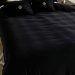 Luxurious black velvet bed with golden-accented pillows and a stylish bedside lamp.