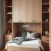 Small bedroom with multi-functional furniture including a bed with storage drawers and wall-mounted shelves.