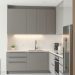 A minimalist kitchen with gray cabinets, white countertops, and modern appliances.