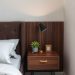 A compact nightstand with storage, featuring a drawer, a lamp, and a small plant.