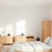 A minimalist Scandinavian bedroom featuring light colors and natural wood furniture.
