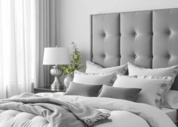 A grey bedroom featuring a plush bed with grey bedding, a tufted headboard, and light curtains.