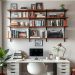 A modern home office with open shelving filled with books and decor above a clean desk with a computer.