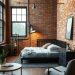 A stylish industrial chic bedroom featuring exposed brick walls, a cozy bed, and modern furniture.