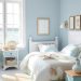 A coastal-themed bedroom with blue walls, white furniture, and nautical decor.