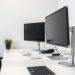 A clean home office setup featuring two monitors, a keyboard, mouse, and a small plant on a desk.