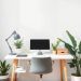 A minimalist home office with a clean desk, comfortable chair, and plants.