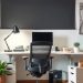 A modern home office setup featuring an ergonomic chair, a spacious desk, and decorative plants.