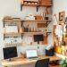 A well-organized home office with wall-mounted shelves and a pegboard for storage.
