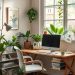 A cozy and inviting home office with a wooden desk, computer, and various indoor plants.