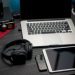 A modern work from home setup featuring a laptop, tablet, smartphone, and headphones on a desk.