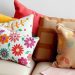 A collection of colorful throw pillows on a couch, featuring floral patterns and various textures.