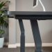 A modern adjustable height standing desk with a sleek design and a computer monitor on it.