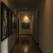 A dimly lit hallway with artwork on the walls, showcasing shadows and reflections.