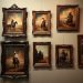 A collection of vintage western paintings featuring cowboys on horseback, displayed in ornate frames.